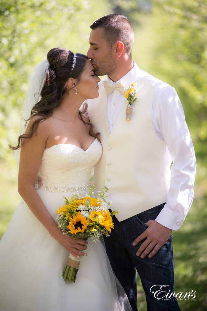 The groom kisses his newly found wife while celebrating their new marriage.