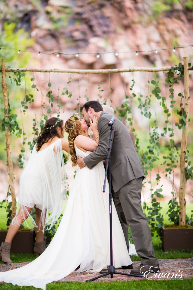 man in black suit kissing woman in white wedding dress