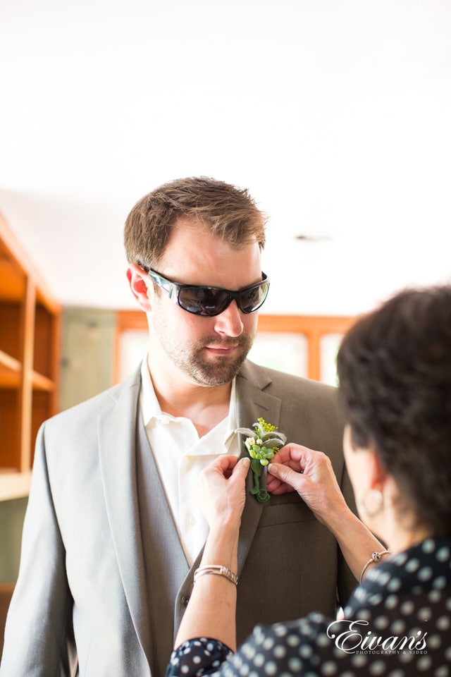 man in white suit holding green flower