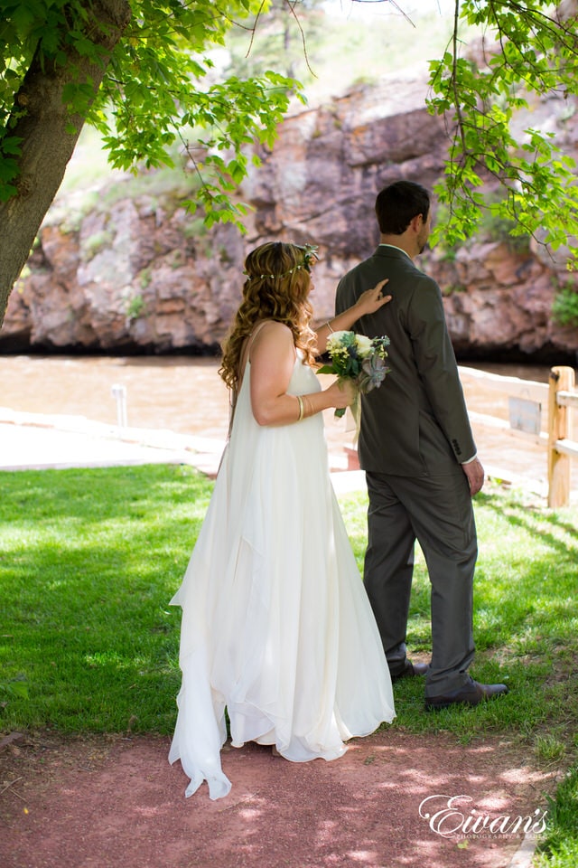 man in black suit kissing woman in white wedding dress on green grass field during daytime