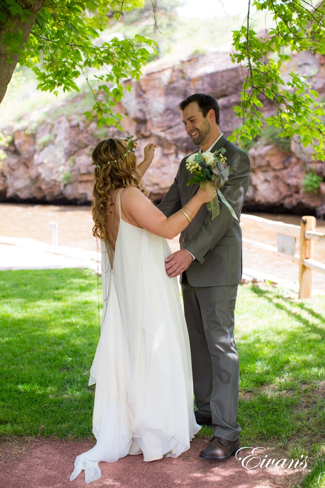 man in gray suit and woman in white wedding dress standing on green grass field during