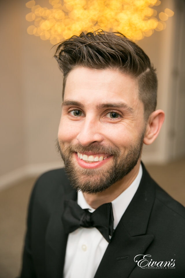 The groom smiles wide for a portrait.