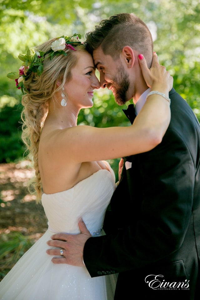 A closeup shot of bride and groom looking into each other's eyes in a wooded area.