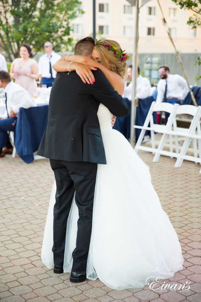 A bride and groom envelop in a tight hug during a dance at their reception.