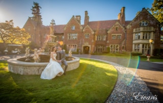 Bride and groom have a seat by the fountain as they pose for wedding portraits.