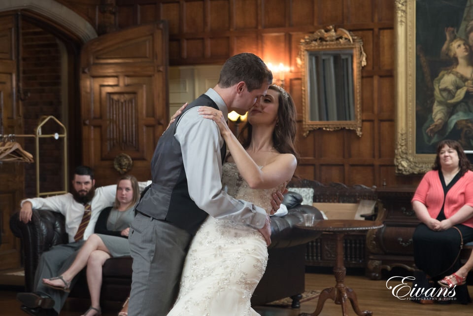 Groom dips his bride during a romantic dance at their reception in an oldfashioned Victorian style home.