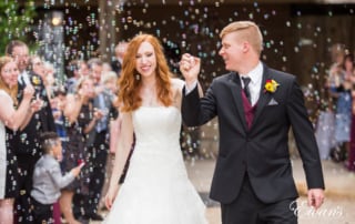 Smiling while exiting their ceremony the couple feels immense amounts of joy and pure happiness. Their friends and family blow bubbles while this moment is shared with all of them.