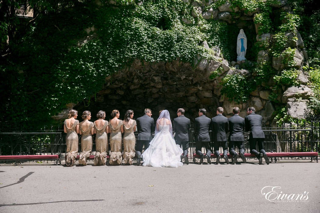 The couple and their counterparts kneel in front of a beautiful wall with lots of gorgeous ivy.