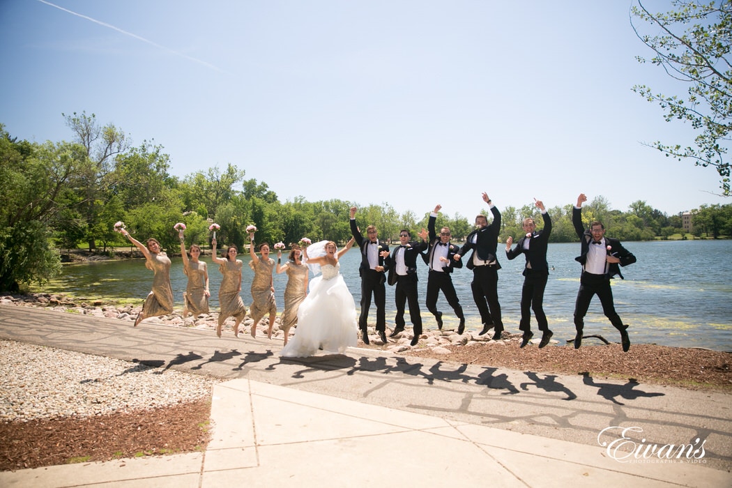 The groom and bride with their closest friends jump and smile with lots of joy and only happiness.