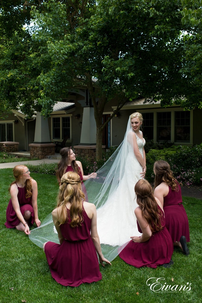 The bride's bridesmaids help hold her amazing long elegant veil supporting her entirely.