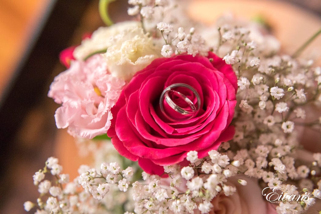 Within the gorgeous hot pink rose it holds the rings that will solidify their love.
