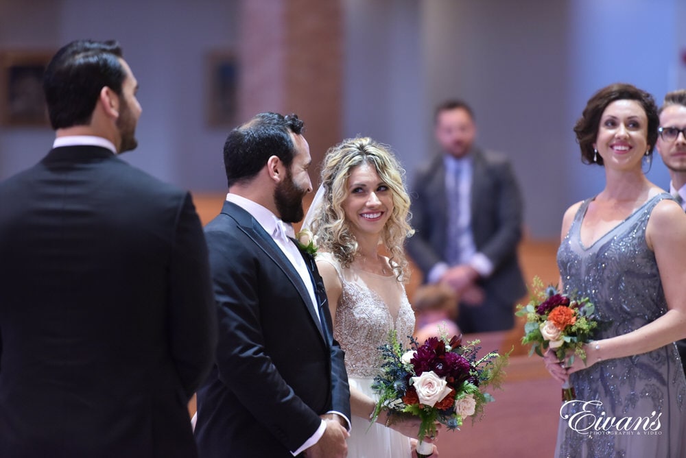 The couple gleam at one another while standing at the alter prepared to start their life together.