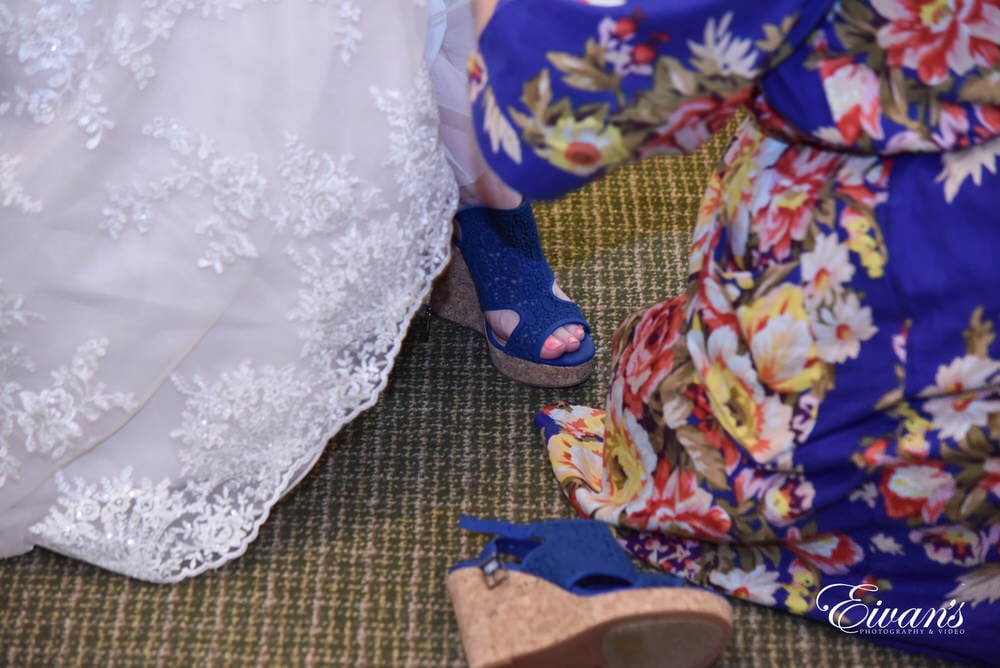 The bride puts on her blue lace wedge heels just before she walks down the isle.