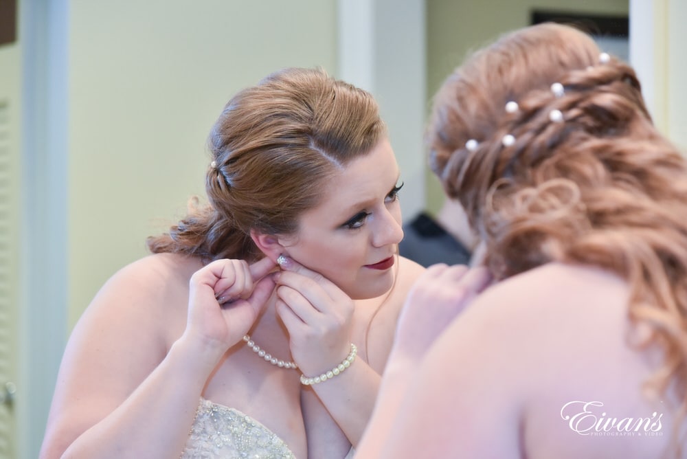 The bride puts on her dazzling earrings that will sparkle tremendously.