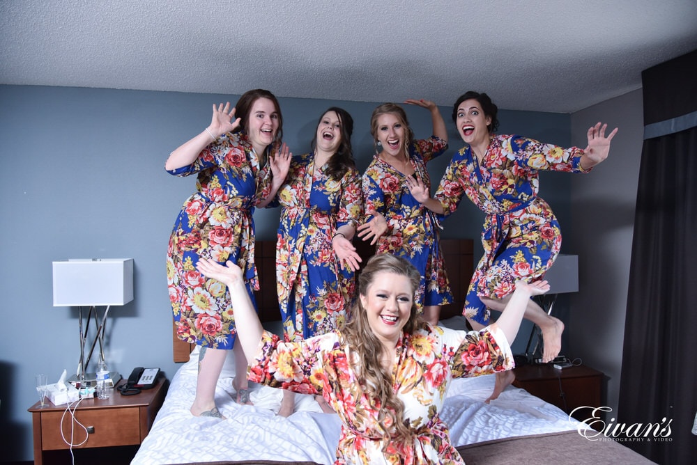 The bride and her bridesmaids smile and jump around preparing for such a fabulous day.