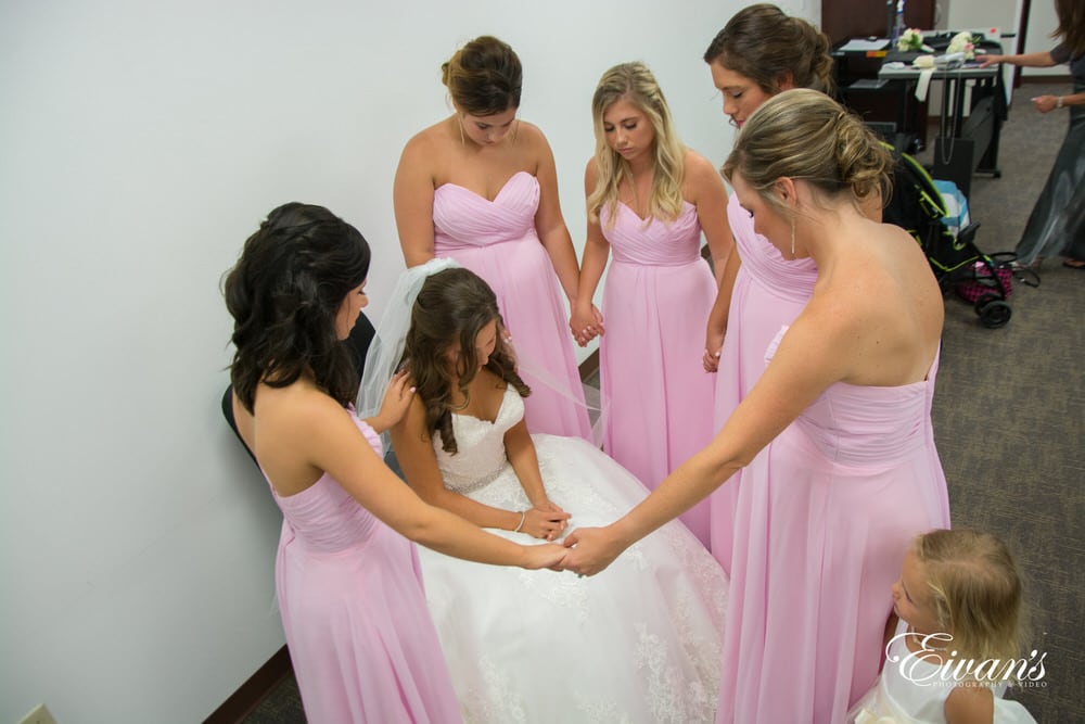The bride and her bridesmaids pray before she walks down the isle to her loved one.