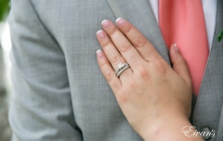 The bride places her hand onto the chest of her groom showing off her new wedding ring.