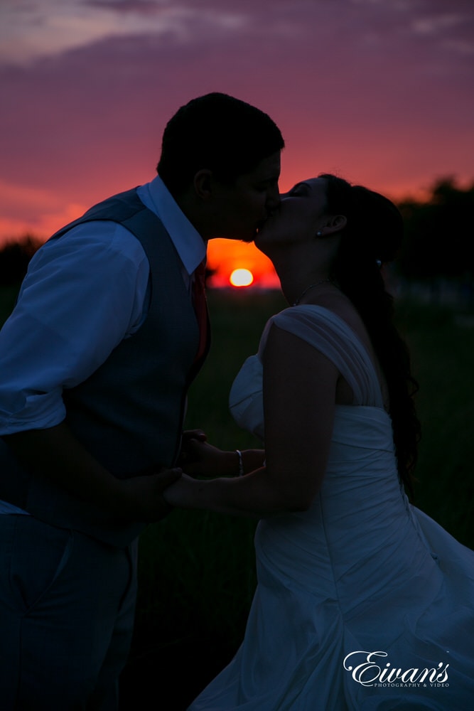 The bride and groom kiss with the sun being their main and centralized piece of this couple's wedding.
