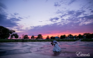 The bride and groom dance together in a beautiful environment under a tremendous sunset.