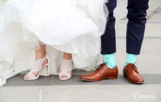 The bride and groom show off their shoes within their perfect wedding day look.