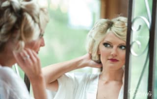 The bride looks at her stunning makeup while waiting for her hair to curl perfectly.