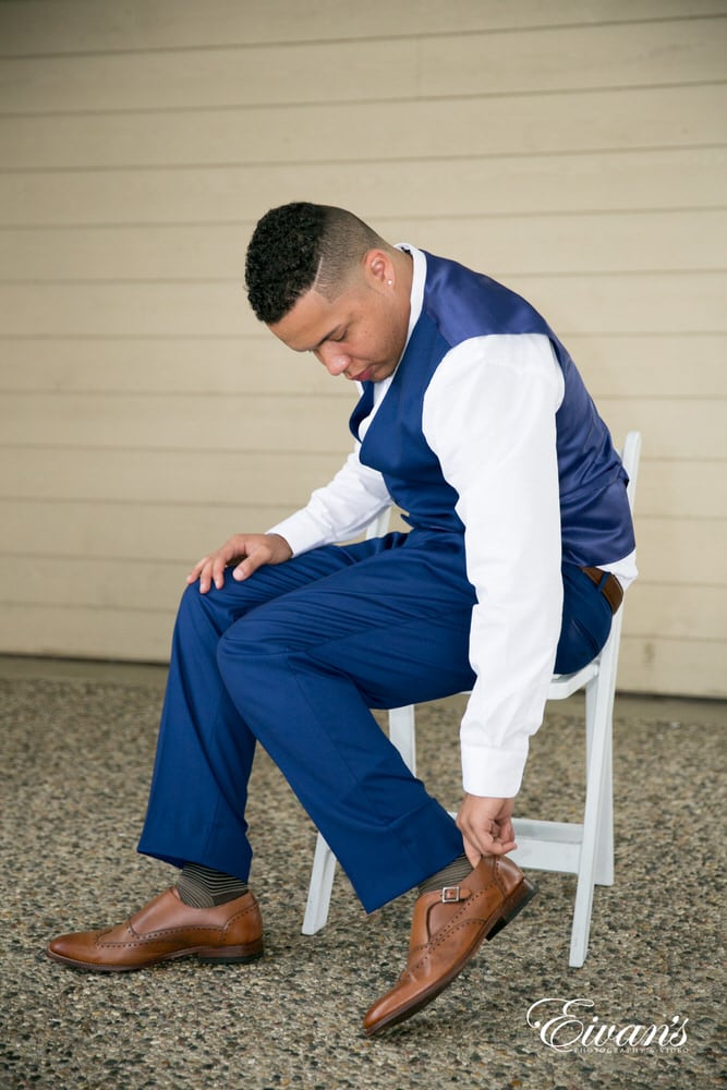 The groom puts on his shoes preparing to see his beautiful bride walk down the isle.