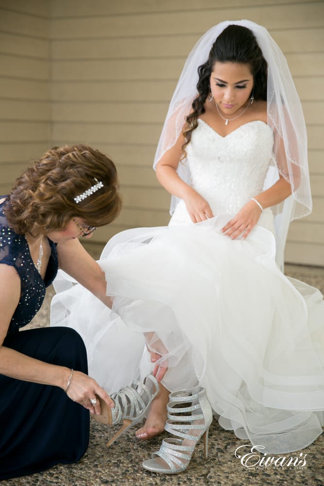 The bride puts on her sparkling silver shoes that completes her look beautifully.