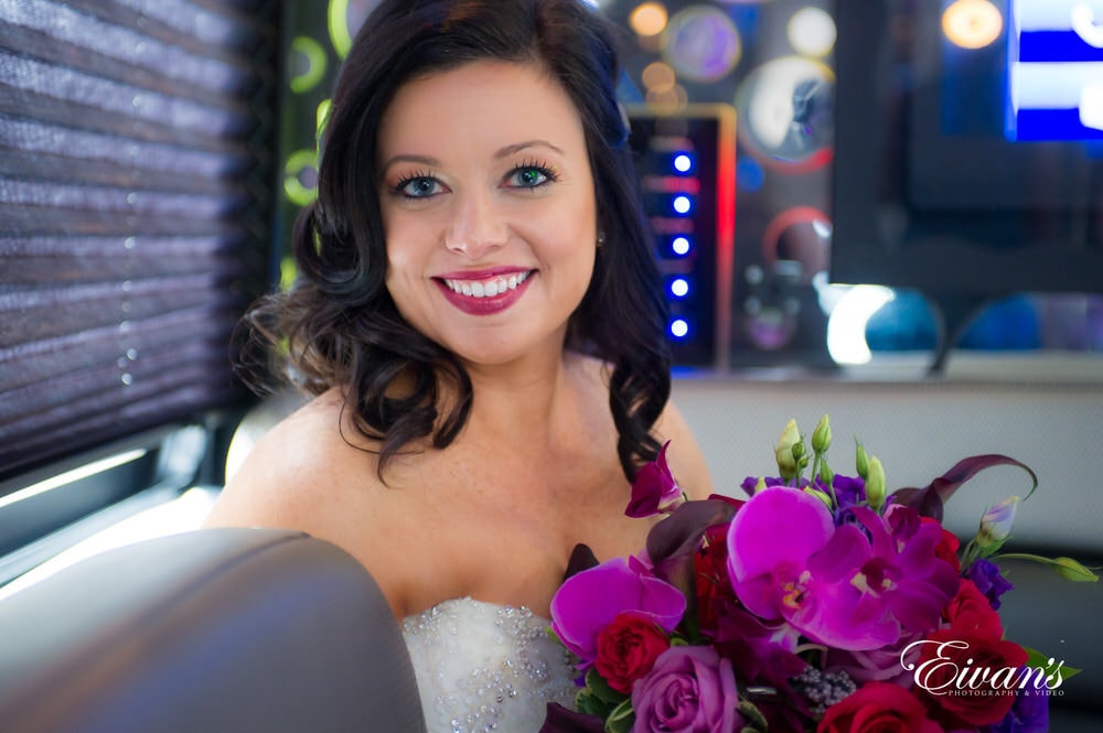 The bride beams while holding her gorgeous vibrant bouquet.