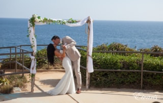 The bride and groom kiss under a stunning archway together kissing and celebrating their love.