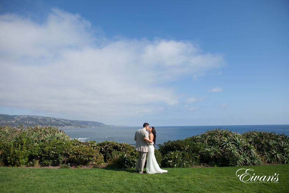 The bride and groom gaze over the beautiful hills into the dazzling blue ocean with all the promise of the world at their fingertips.