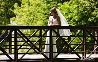 Standing so beautifully on a bridge the bride has the sun shining down on her making her shimmer.