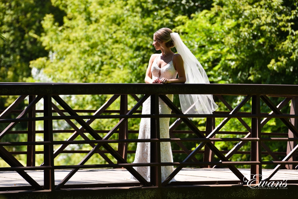 Standing so beautifully on a bridge the bride has the sun shining down on her making her shimmer.