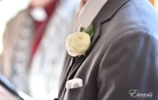 The groom's boutonniere is a white rose that fits onto his slate grey suit so well.