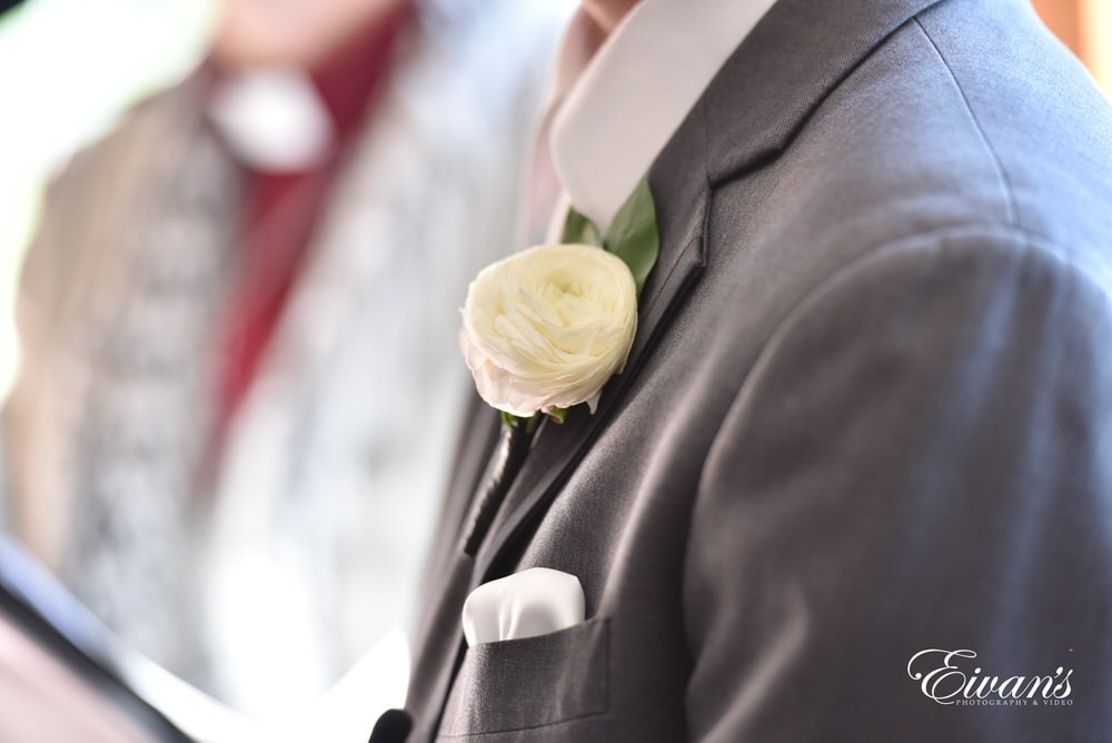 The groom's boutonniere is a white rose that fits onto his slate grey suit so well.