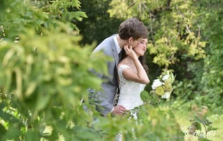 The groom kisses the cheek of his bride while they are entirely surrounded by mother nature.