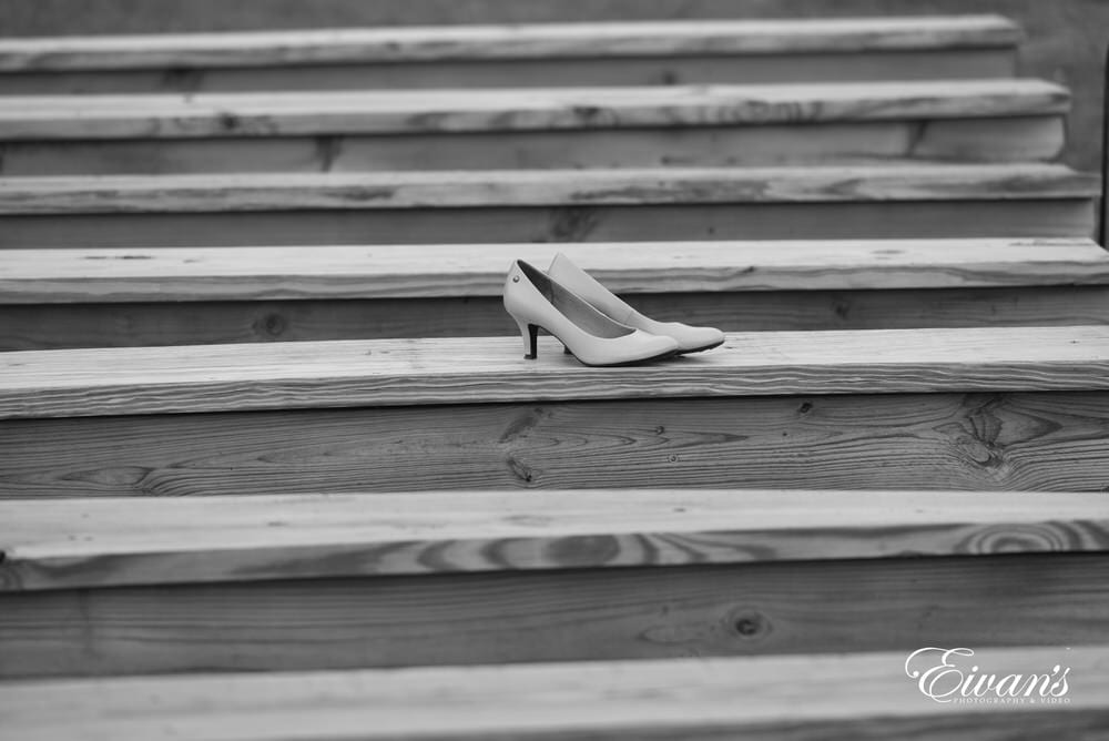 The bride's heels lay upon the rustic wooden benches that the couple's loving friends and family will soon fill.