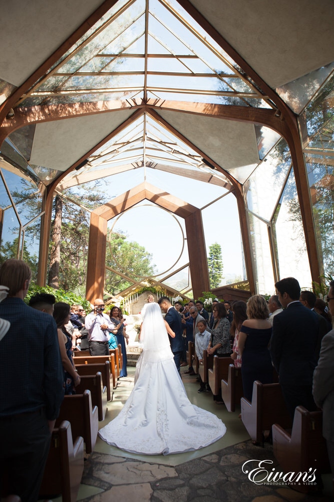 The bride walks down the to the alter to her beloved in a beautiful church with the shining sun.