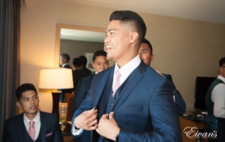 The groom beams with love and happiness as he prepares to his amazing bride.