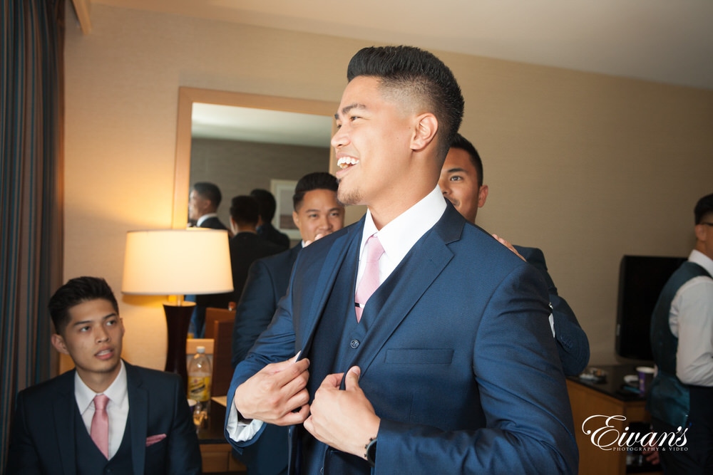 The groom beams with love and happiness as he prepares to his amazing bride.
