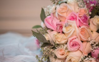 The brides bouquet of white and pink roses is also holding the ring that will soon be placed onto her finger.