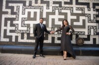 eivans_gallery_engagement_photos_128 A newly engaged couple holding hands in front of a patterned wall outdoors.