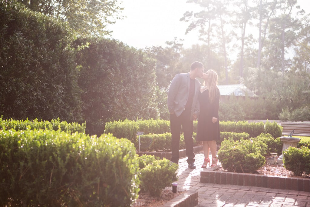 A young couple kiss in the garden on a beautiful sunny day.