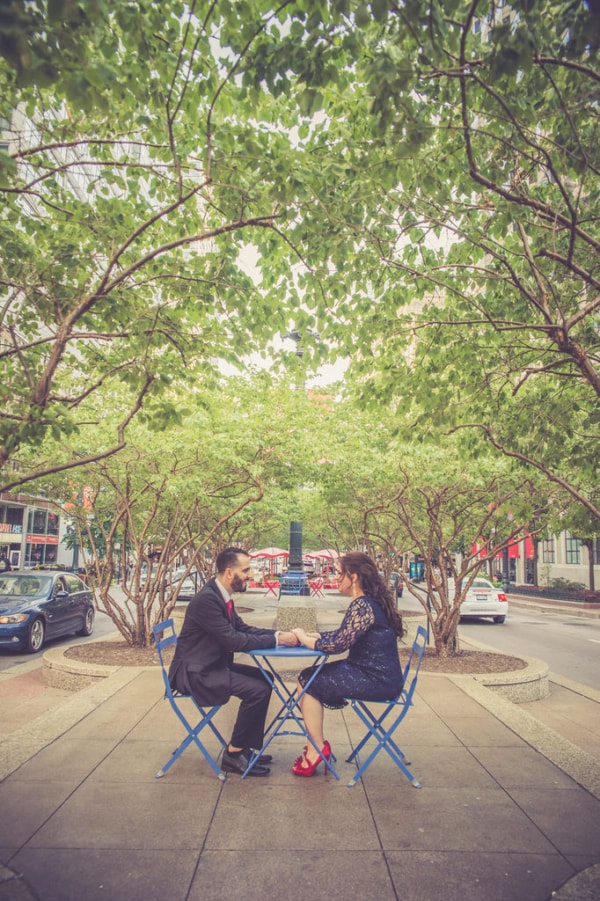 This couple sits at a bright blue set of tables and chairs while it is placed in the center of a very busy road. They hold hands and smile relentlessly because all they are sharing is their everlasting love. The red and blue in the scenery is complemented by the couple's looks, it makes this photograph more than pleasing to the eyes.