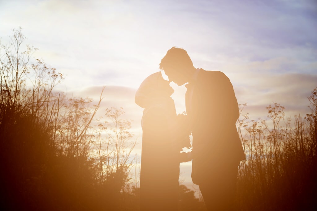 The photographer captures a beautiful silhouette of a young couple in a wildflower field.