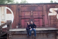 Wedding / Engagement Photography A newly engaged couple sits on a deck next to a freight train.
