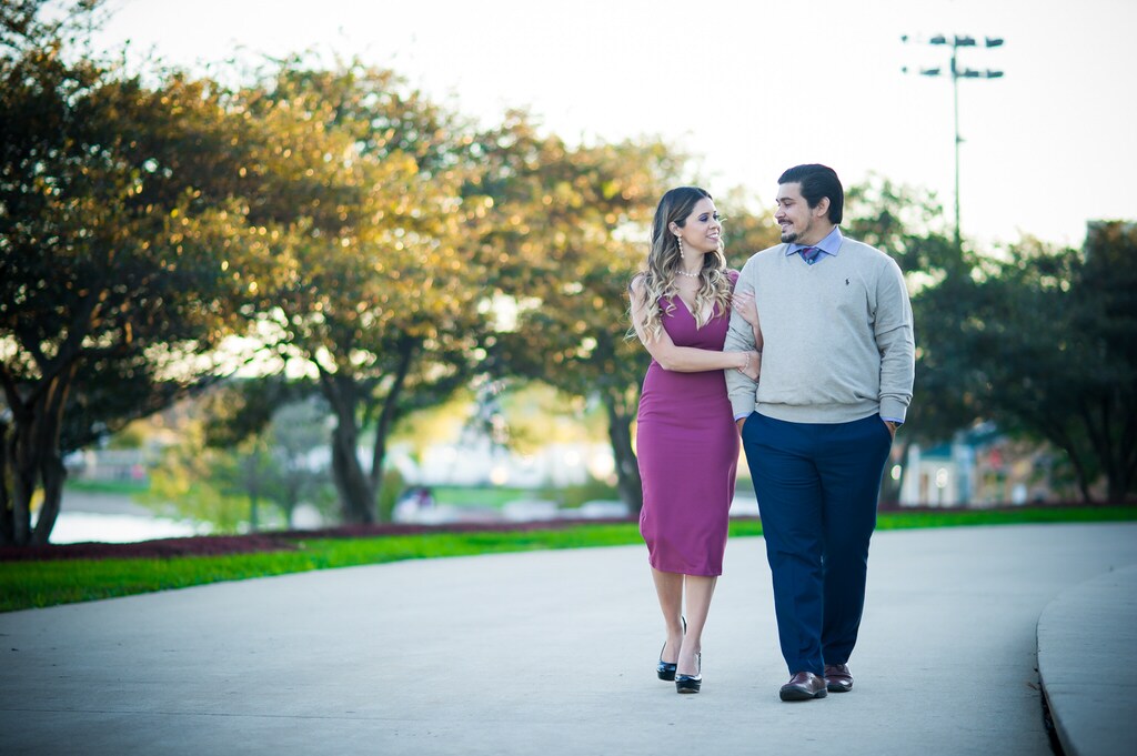 A couple strolls arm-in-arm looking at each other happily.