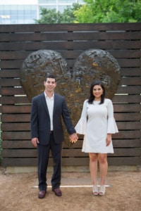 eivans_gallery_engagement_photos_186 A newly engaged couple holds hands and smiles in front of a large heart sculpture.