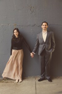 eivans_gallery_engagement_photos_194 This couple stands against a slate grey wall holding hands ever so slightly yet so tightly that their love can be shown with one small gesture. Smiling away their love and all desires of happiness.