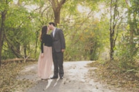 eivans_gallery_engagement_photos_195 A young couple shares a kiss on a forest trail for their engagement shoot. The woman wears a flowy, pink chiffon maxi skirt with a black, leather waist belt.
