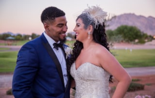 Fashion photographer captures a joyful moment between Bride and Groom at sunset. The Groom is wearing a handsome blue and black color block tuxedo jacket. The Bride is wearing a lovely vintage birdcage visor and drop pearl earrings.